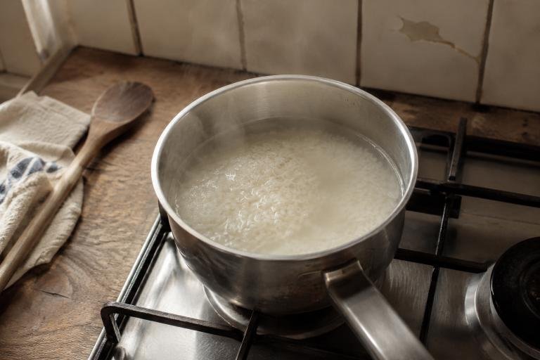 A pot of rice cooking in water on a stovetop, drained to reduce arsenic levels per FDA guidance
