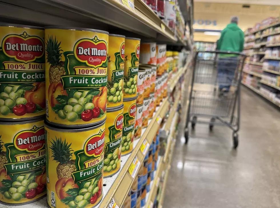 Canned fruit cocktail on a grocery store shelf under a food recall notice