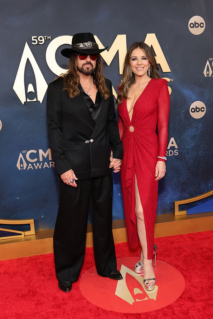 The 59th Annual CMA Awards - Arrivals Billy Ray Cyrus and Elizabeth Hurley smiling together on a red carpet appearance